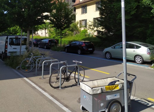 Route d'accès au lotissement Riedtli : rue à sens unique avec une bande cyclable en sens contraire ainsi qu’un parking à vélos public (photo : Mobilservice) 